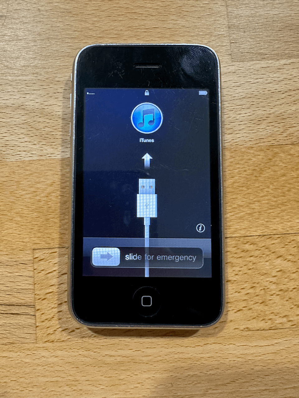iPhone 3G stuck showing a cable and to connect to iTunes. Also slide for emergency.